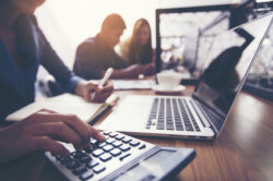 The hands of a female accountant are using a calculator to calculate taxes.